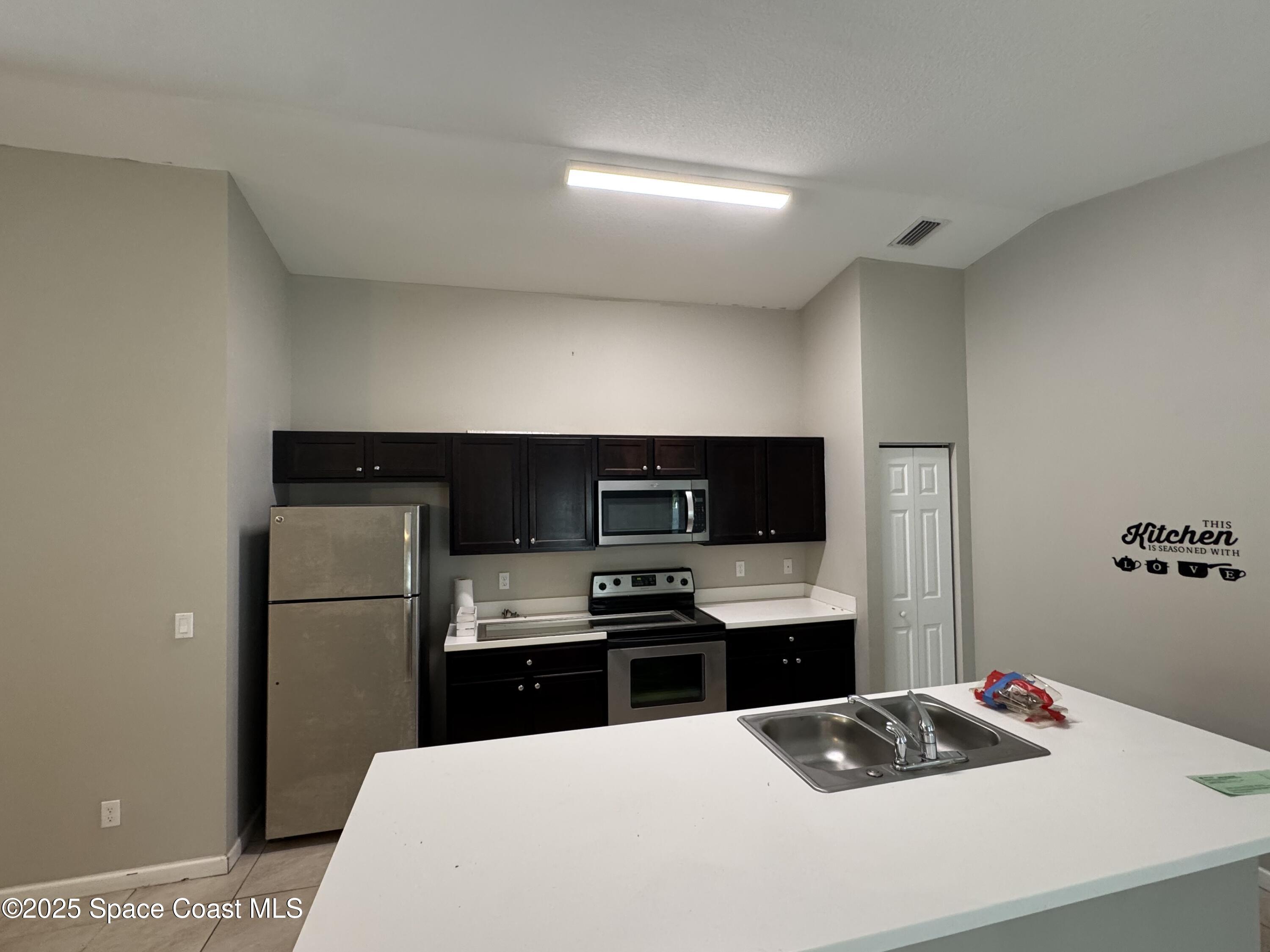 3925 Southwest Laffite Street Port St. Lucie, FL 34953 - Photo 10 of 20 a kitchen with stainless steel appliances a refrigerator stove and microwave
