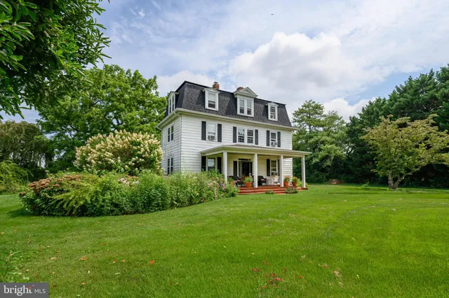 a view of a house with a big yard plants and large trees
