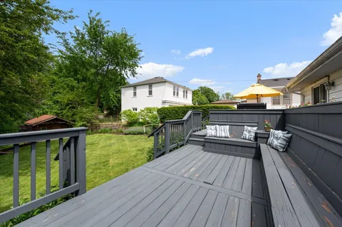 a view of a house with backyard wooden deck and furniture