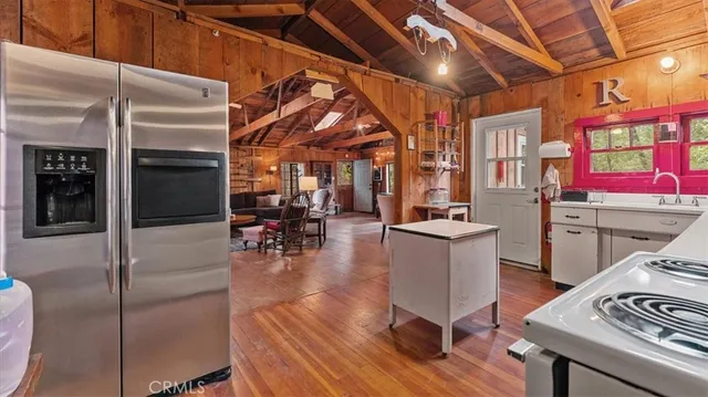 a kitchen with stainless steel appliances kitchen island granite countertop a refrigerator a stove and white cabinets with wooden floor