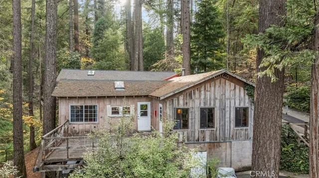 a view of a house with a wooden deck and a large tree
