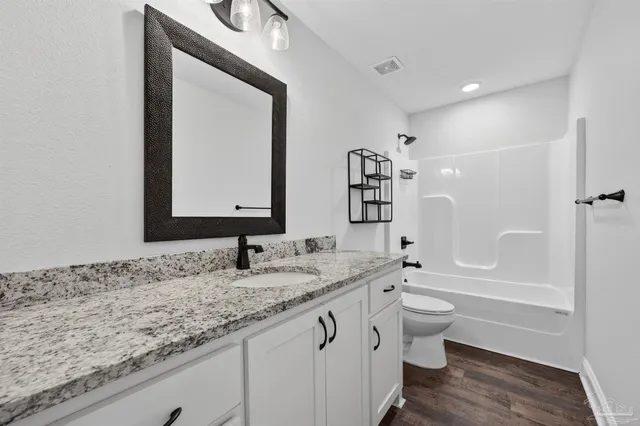 a bathroom with a granite countertop sink mirror vanity bathtub and a toilet