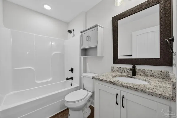 a bathroom with a granite countertop sink toilet mirror and bathtub