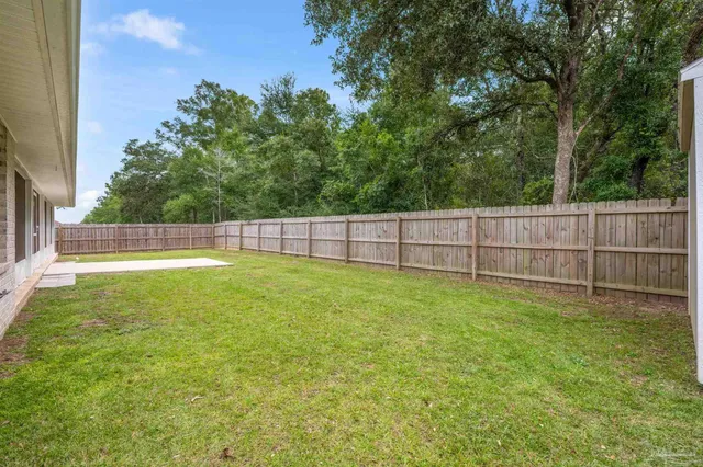 a view of a backyard with a tree and wooden fence
