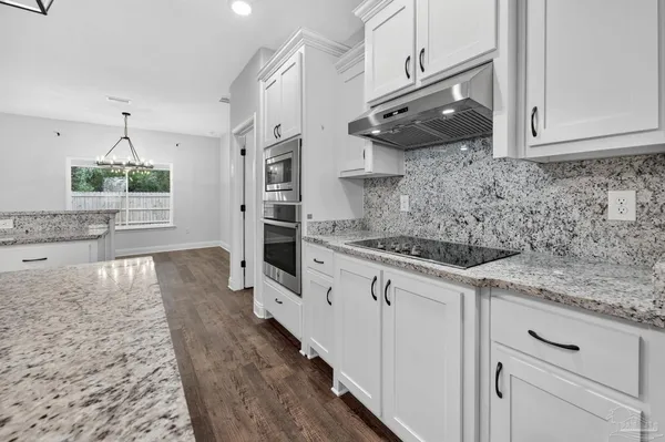 a kitchen with granite countertop a sink stainless steel appliances and cabinets