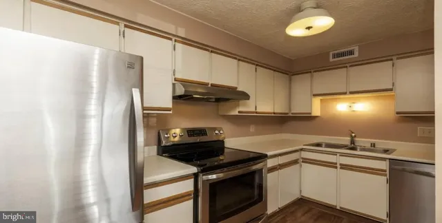 a kitchen with stainless steel appliances a stove a sink and a refrigerator