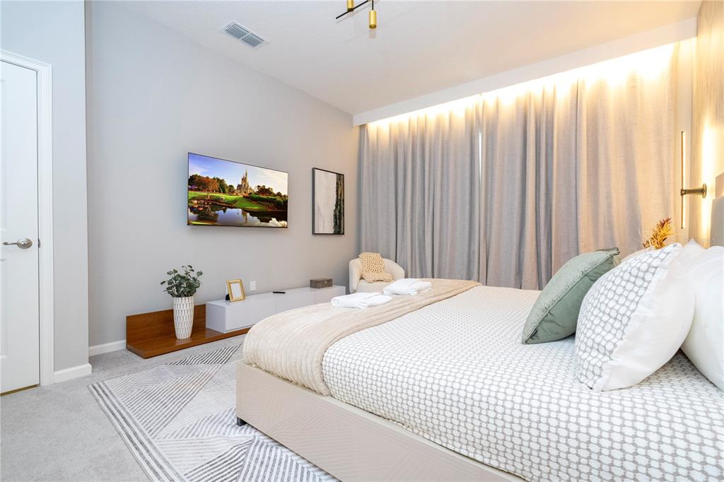 10018 Voyager Way Orlando, FL 32821 - Photo 11 of 100 a bedroom with a bed a couch and a flat screen tv