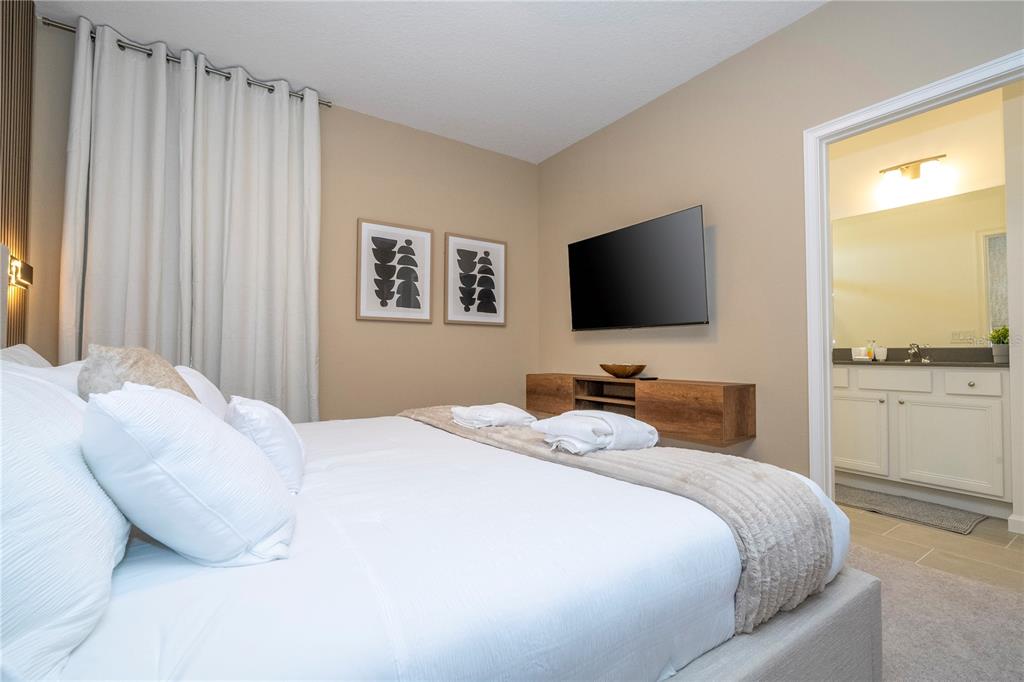 10018 Voyager Way Orlando, FL 32821 - Photo 57 of 100 a bedroom with a bed and a flat screen tv