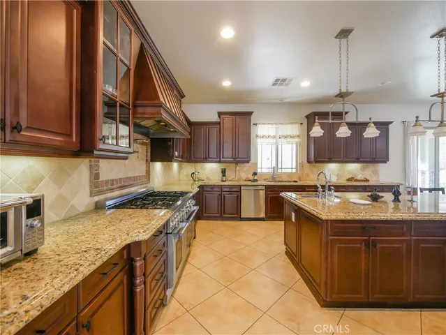a kitchen with stainless steel appliances granite countertop a table chairs sink and cabinets