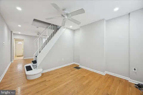 a view of an empty room with wooden floor and stairs