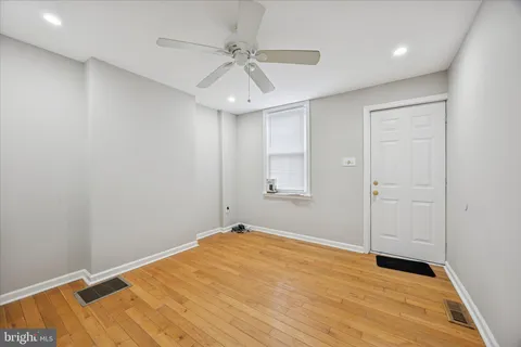 an empty room with a ceiling fan and wooden floor