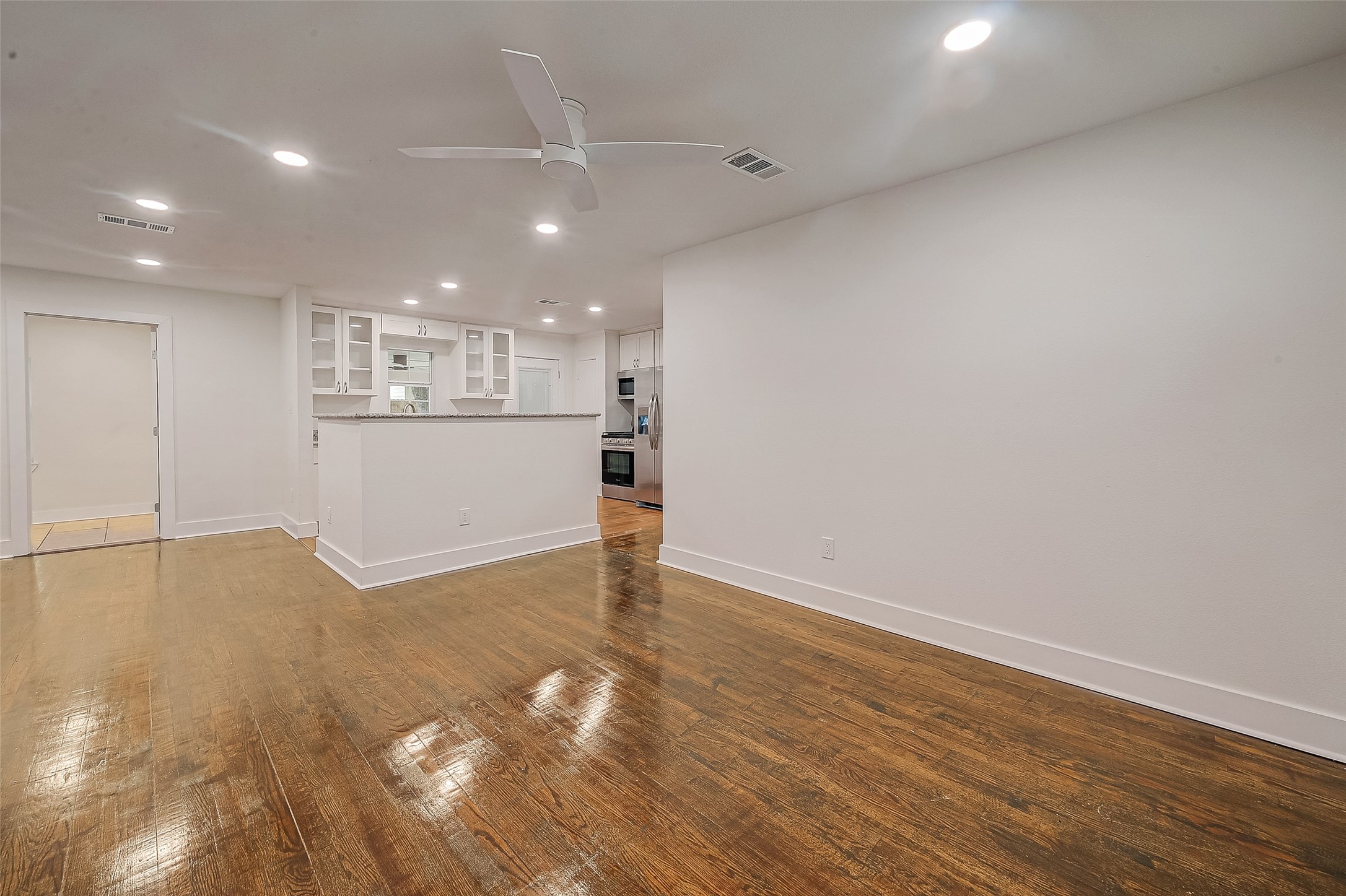 5703 Belmark Street Houston, TX 77033 - Photo 31 of 43 an empty room with wooden floor and kitchen view