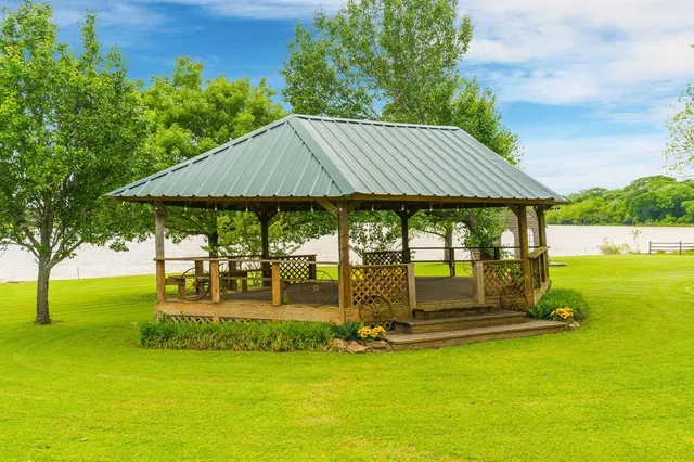 a view of pool with lawn chairs and large trees