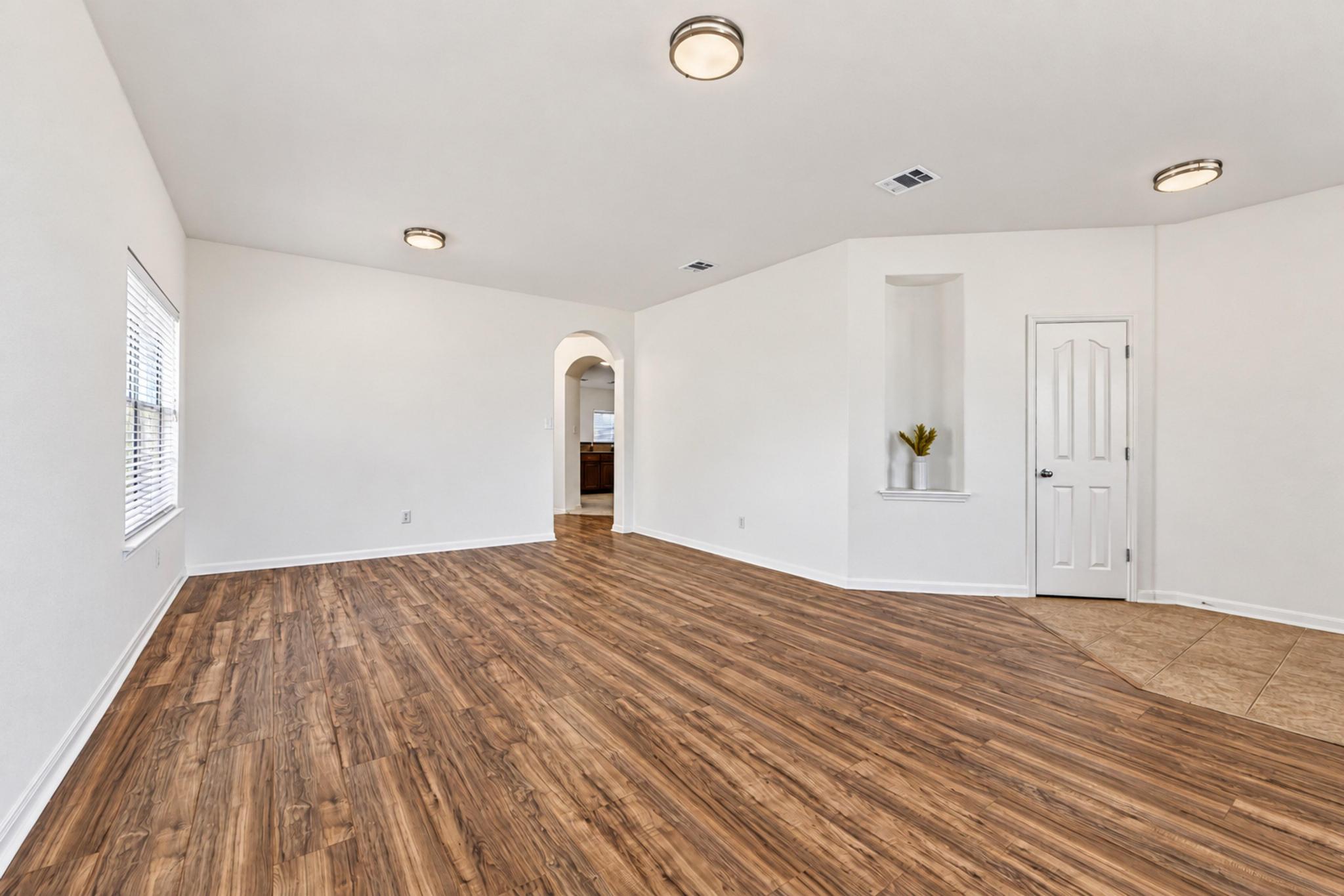 150 Engineers Pass Jarrell, TX 76537 - Photo 8 of 40 Rich wood-look flooring stretches across an open living area featuring neutral walls and arched doorways.