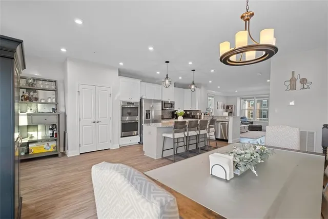a living room with stainless steel appliances furniture wooden floor and a kitchen view