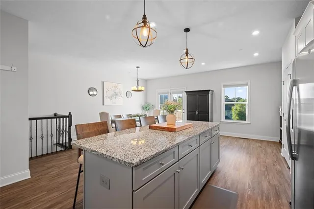 a kitchen with granite countertop kitchen island stainless steel appliances a table chairs sink and microwave