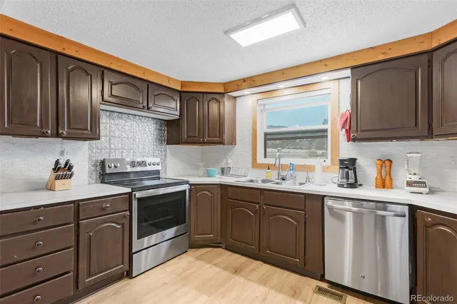 a kitchen with granite countertop stainless steel appliances a sink dishwasher stove and cabinets
