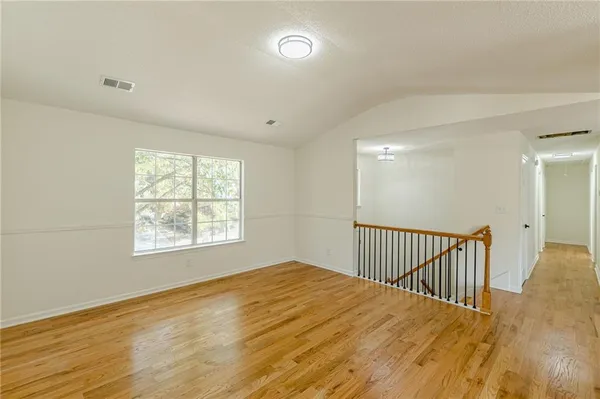 a view of an empty room with window and wooden floor