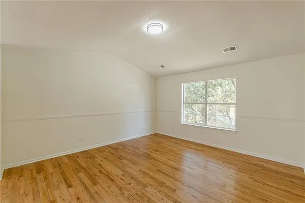 a view of empty room with wooden floor and windows