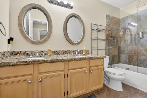 a bathroom with a granite countertop toilet a sink and a mirror
