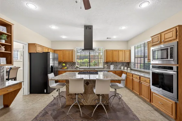 a kitchen with stainless steel appliances a dining table chairs refrigerator and cabinets