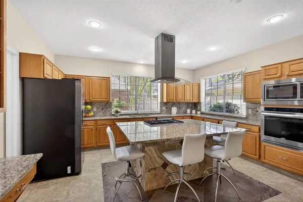 a kitchen with stainless steel appliances granite countertop a stove a refrigerator a kitchen island with a stove and white cabinets