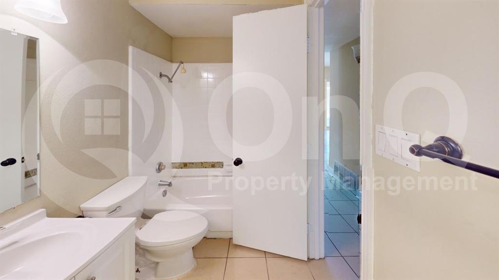 3005 Meandering Way Bedford, TX 76021 - Photo 9 of 24 Bathroom featuring a white vanity with integrated sink, coordinating white toilet, and a white bathtub with an overhead shower fixture