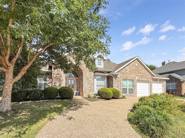 a front view of a house with a dirt yard and a large tree