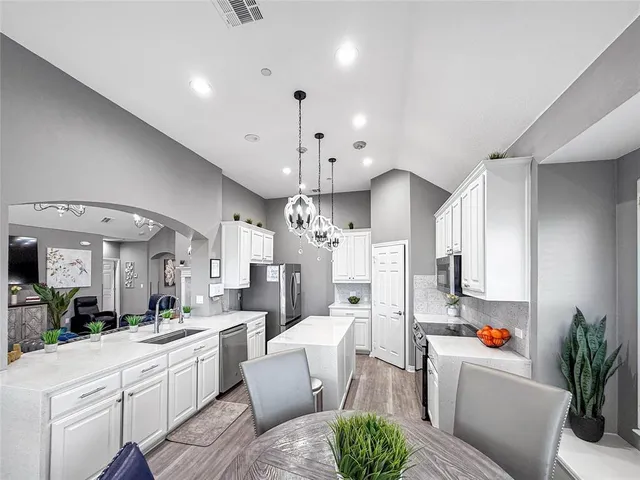 a large white kitchen with a refrigerator a stove a sink dishwasher and white cabinets with wooden floor