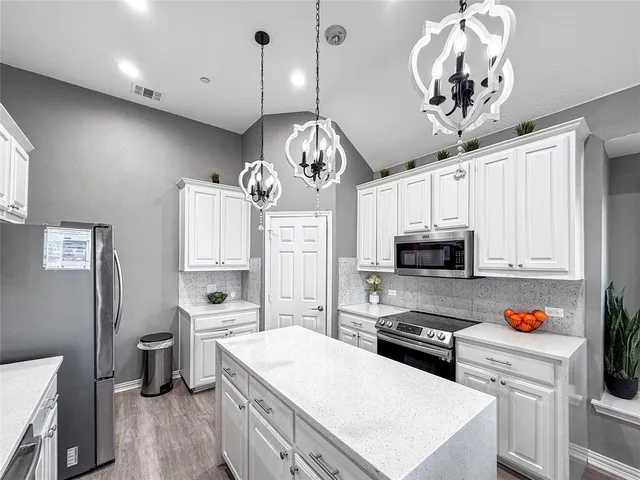 a kitchen with stainless steel appliances a stove refrigerator a sink dishwasher and white cabinets with wooden floor