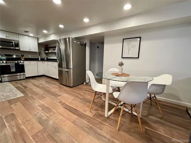 a kitchen with a dining table chairs refrigerator and microwave