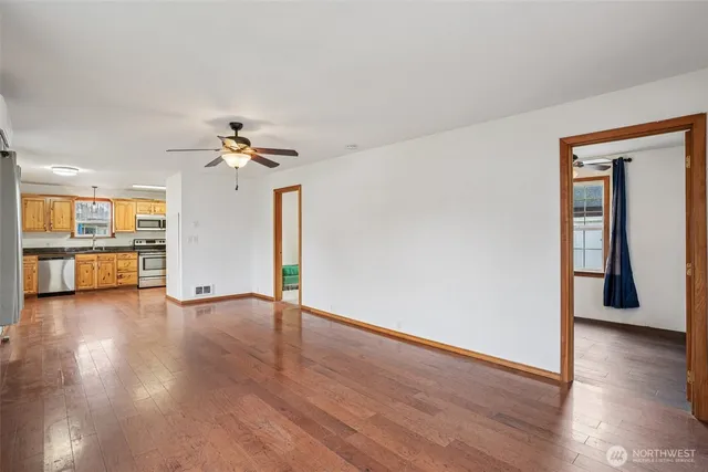 a view of an empty room with wooden floor and a window