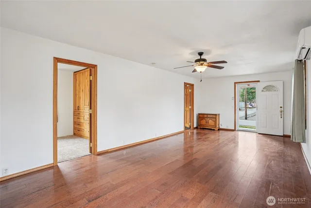 an empty room with wooden floor and ceiling fan