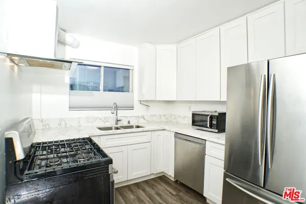 a kitchen with white cabinets and appliances