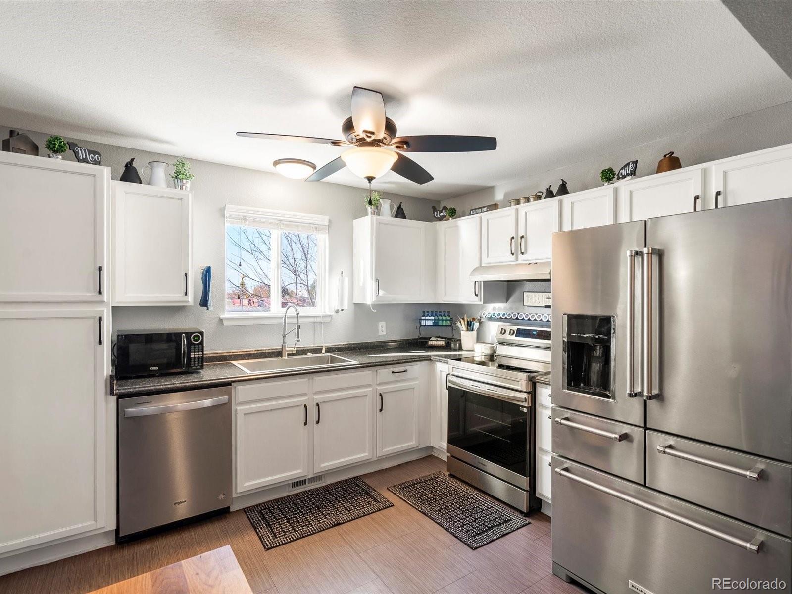 9657 Ironton Street Commerce City, CO 80022 - Photo 12 of 48 a kitchen with stainless steel appliances a refrigerator sink and white cabinets