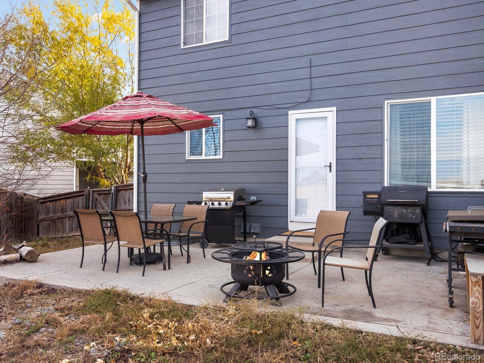 9657 Ironton Street Commerce City, CO 80022 - Photo 43 of 48 a view of a backyard with table and chairs under an umbrella