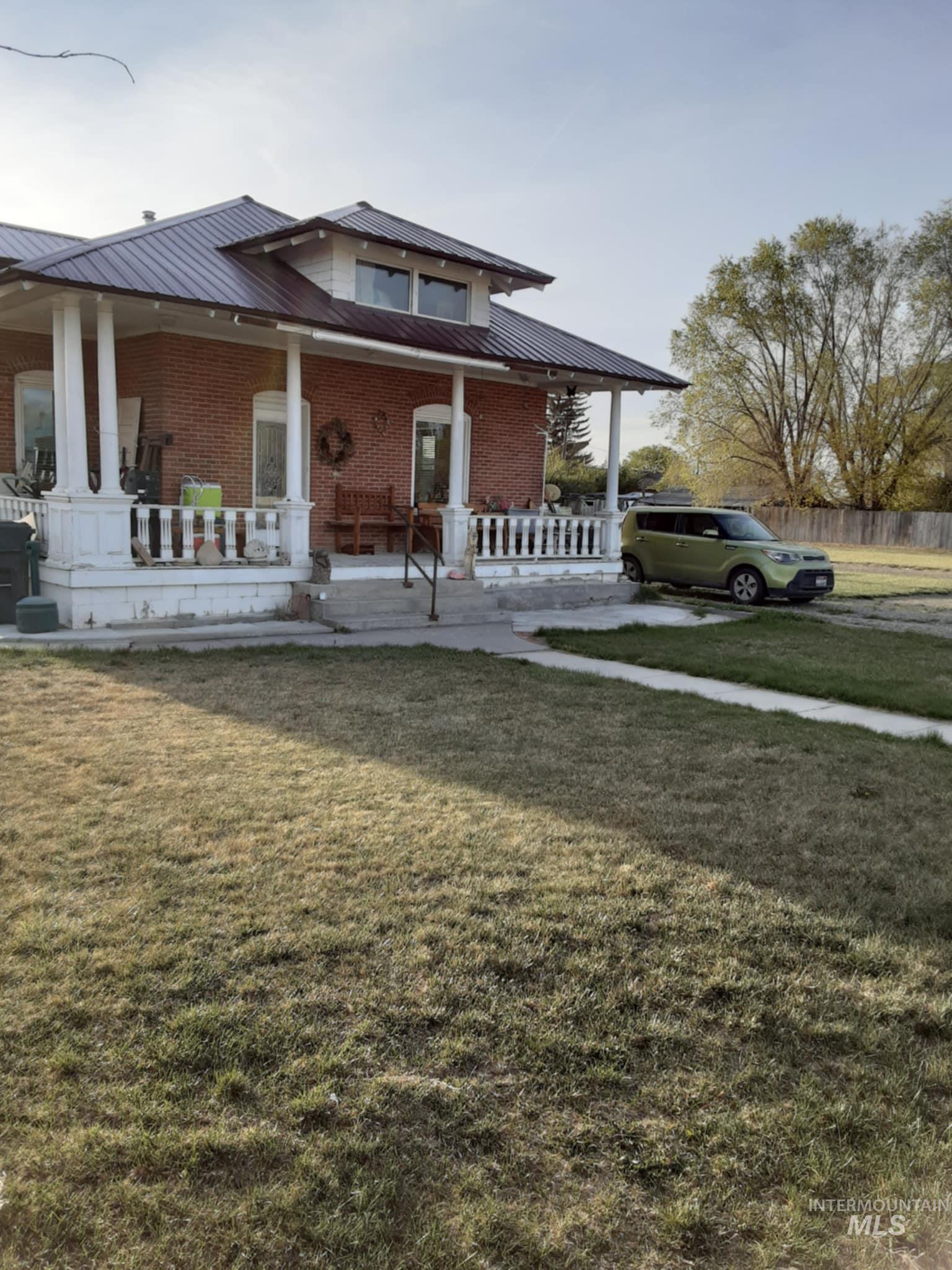 View of front of home with a front yard, a porch, and brick siding