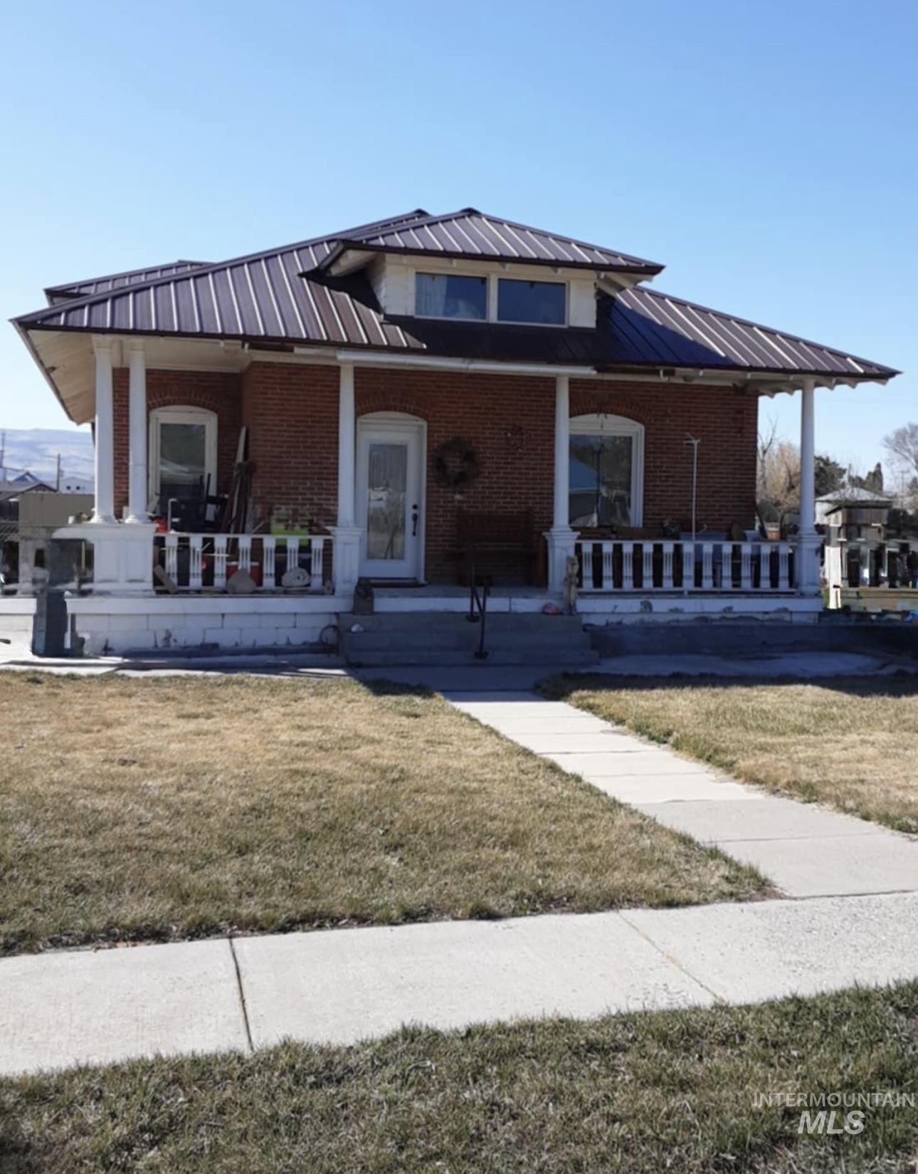 145 North Lincoln Avenue Oakley, ID 83346 - Photo 1 of 48 View of front of home featuring a front lawn, brick siding, covered porch, and a standing seam roof