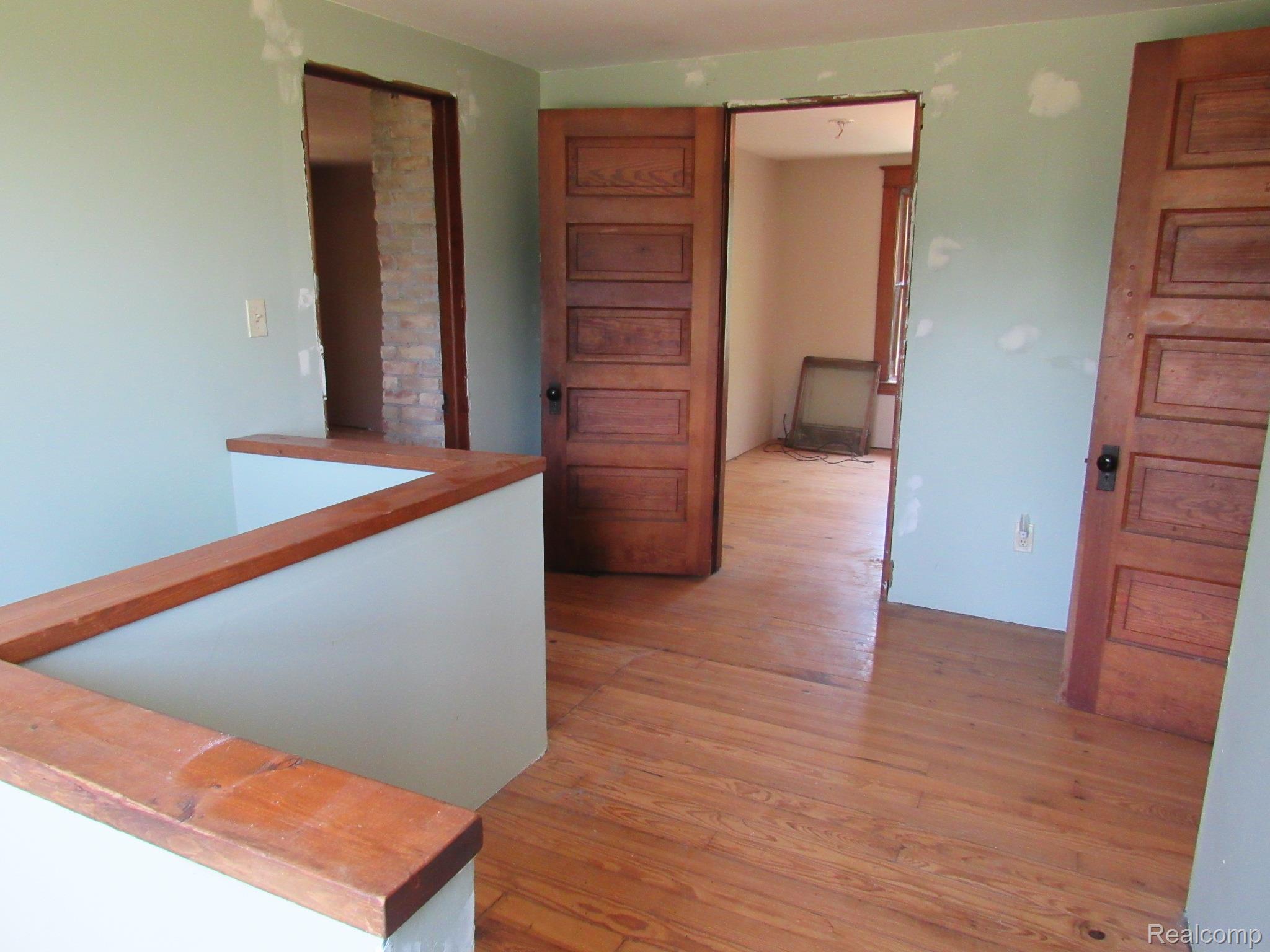 695 Cass Avenue Road Bay City, MI 48708 - Photo 13 of 52 Wood-finish flooring throughout, featuring two paneled doors with dark hardware, and a partial wall with a wood-finish cap