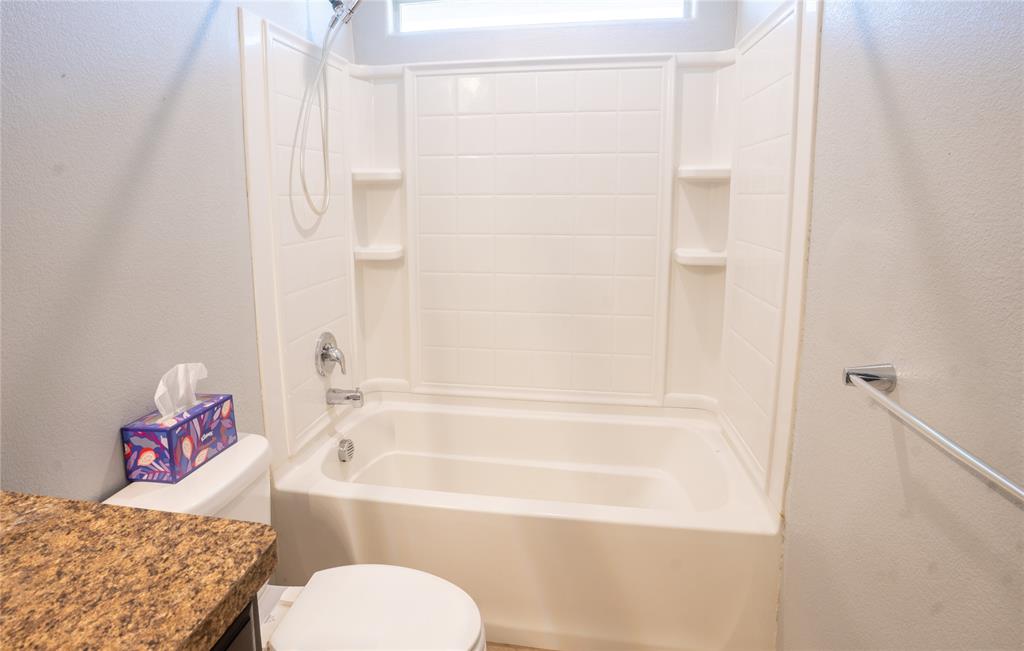 753 Rutherford Drive Crowley, TX 76036 - Photo 25 of 26 Bathroom featuring a white tub and shower combination with a built-in shelving unit, chrome fixtures, and a showerhead with a flexible hose
