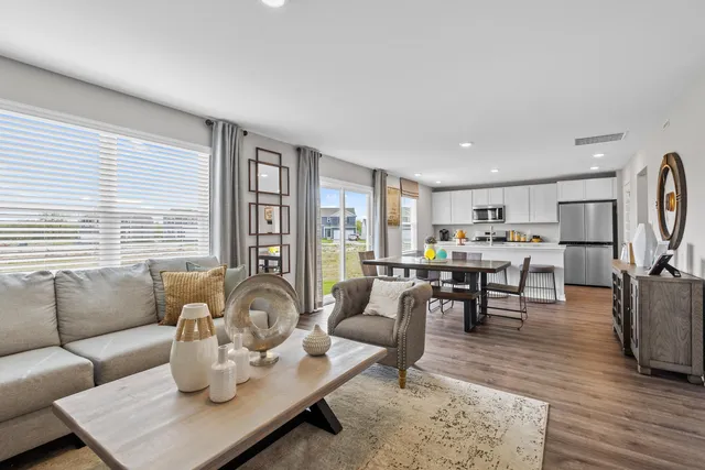 a living room with furniture kitchen view and large windows