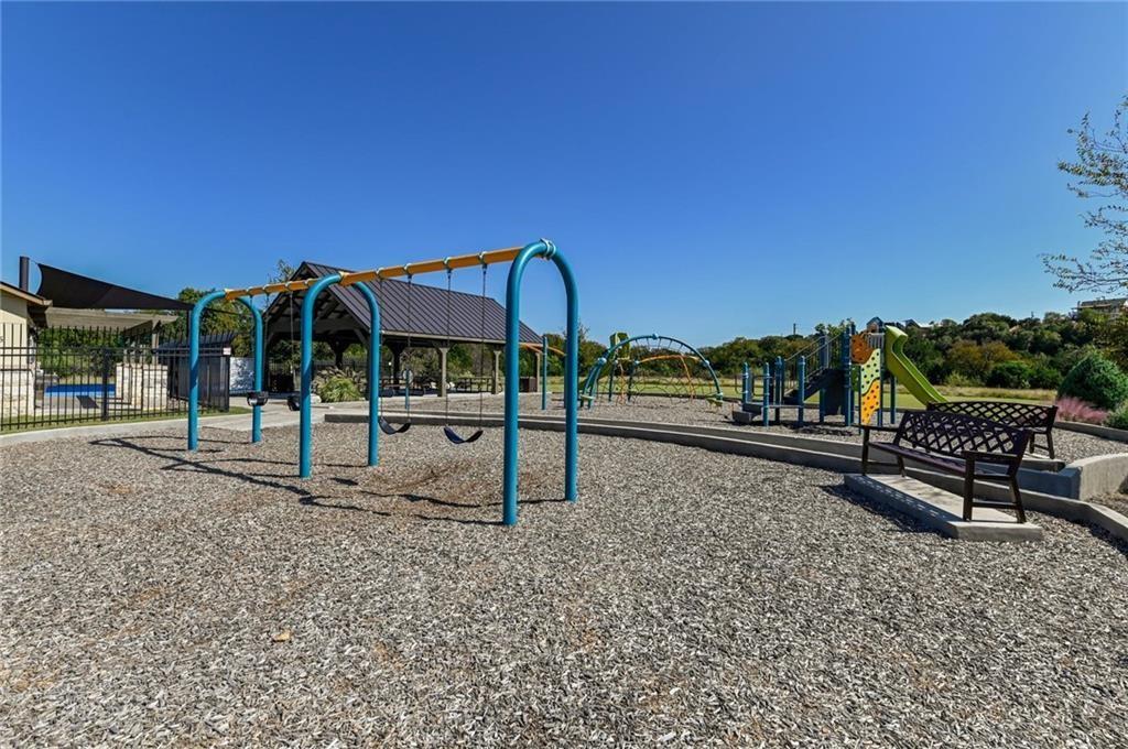 375 Housefinch Loop Leander, TX 78641 - Photo 25 of 28 A well-maintained neighborhood playground features swings, climbing structures, and a shaded pavilion under clear blue skies.