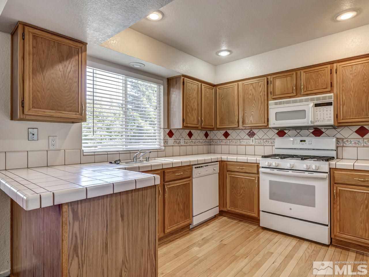 2035 Honey Ridge Drive Reno, NV 89511 - Photo 3 of 25 a kitchen with stainless steel appliances granite countertop a sink a stove a refrigerator cabinets and wooden floor