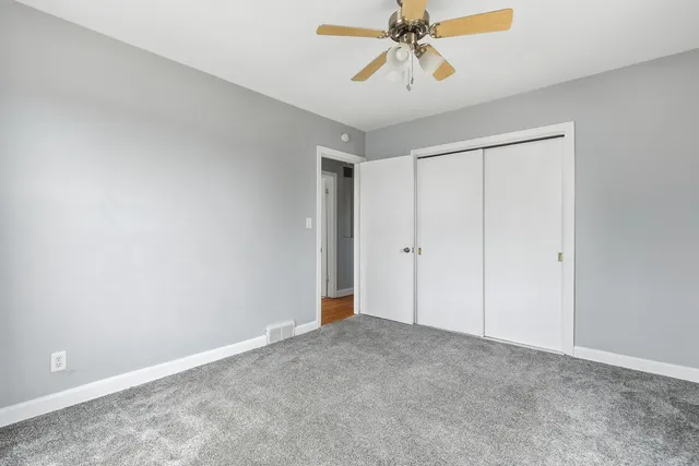 an empty room with a ceiling fan and a window