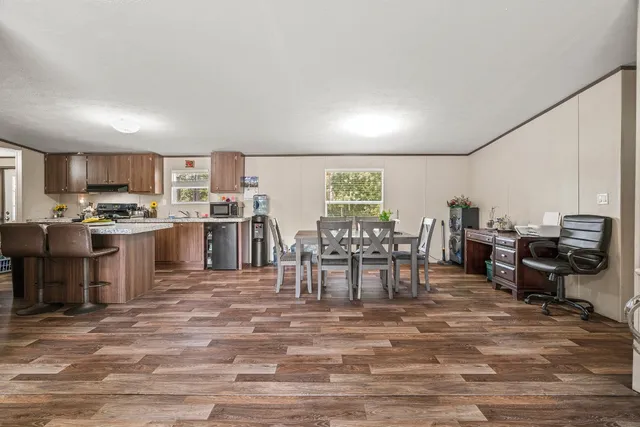 a room with stainless steel appliances lots of wooden furniture a dining table and chairs