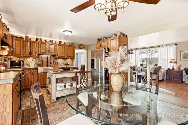 a kitchen with stainless steel appliances granite countertop a stove top oven a sink a dining table and chairs with wooden floor