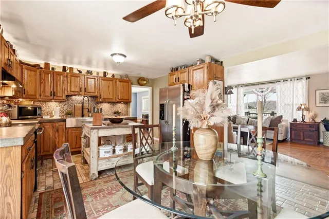 a kitchen with stainless steel appliances granite countertop a stove top oven a sink a dining table and chairs with wooden floor