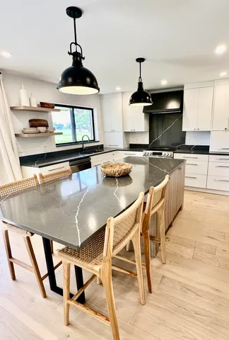 a kitchen with stainless steel appliances kitchen island granite countertop a table chairs in it and wooden floors