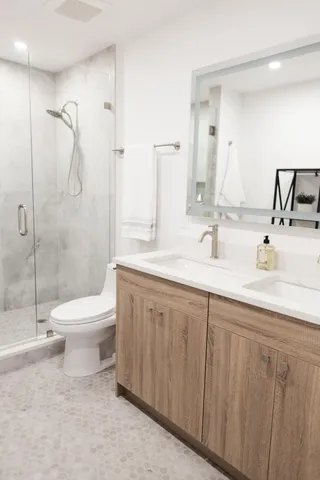 a bathroom with a toilet a sink a mirror and shower