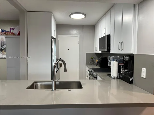 a kitchen with kitchen island granite countertop a sink stainless steel appliances and cabinets